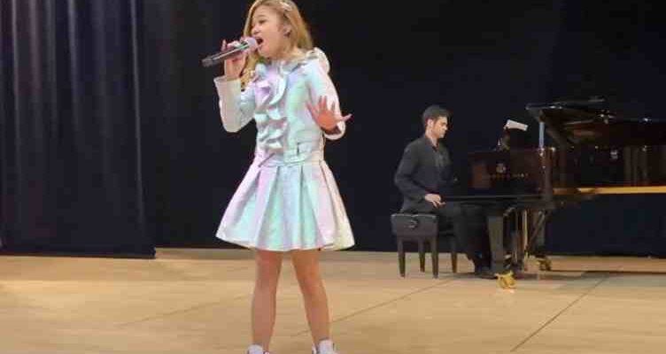 The stage is dominated by the captivating performance of two young girls singing “A Million Dreams.”